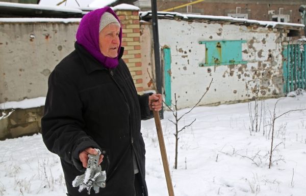 Местная жительница держит в руках хвостовик мины, найденный на участке своего дома после обстрела в поселке Веселое Донецкой области