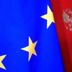 Флаг Евросоюза на фоне стены с гербом РФ