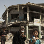 {«ar»:»»,»ru»:»»,»pt»:»Mulheres e crianças andam em meio à destruição em Mossul, no Iraque»,»en»:»Women and children walk through the debris of buildings and vehicles destroyed during intense fighting as they flee for safe areas in Mosul, Iraq.»,»fr»:»